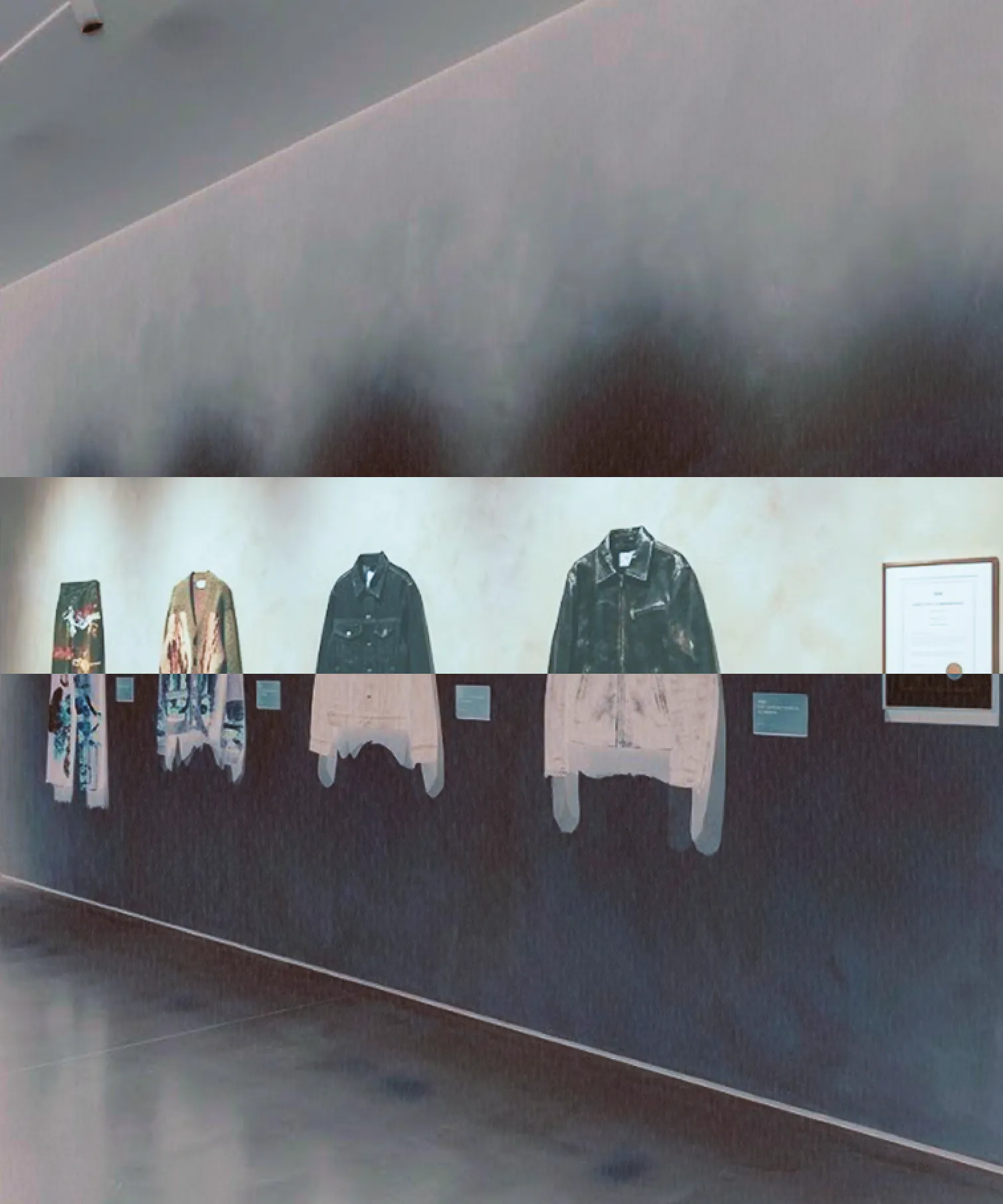 Exhibition wall: a row of garments, cut across by the house's inverted band.